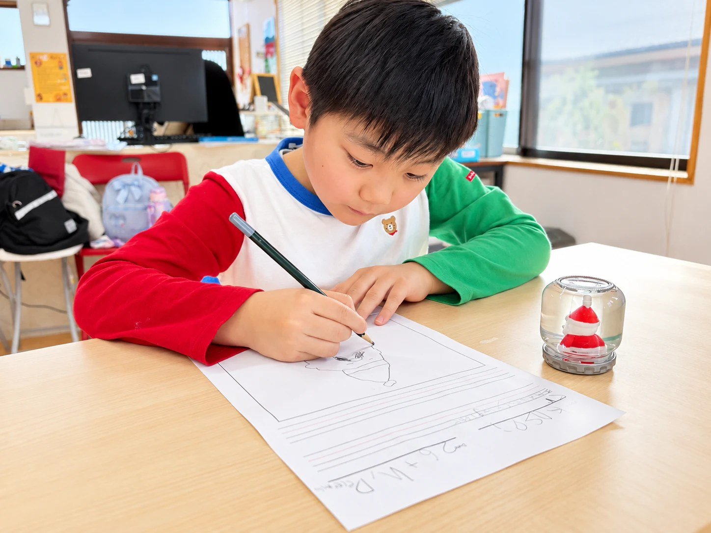 A child writing on a worksheet with a pencil.