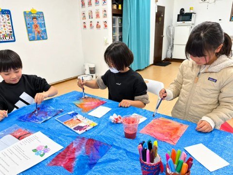Children painting colorful sheets of paper with brushes.