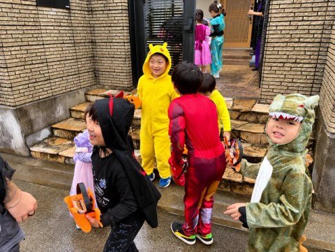 Children in costumes standing together with orange baskets.