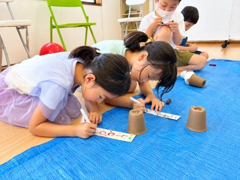 Children in costumes decorating paper strips with markers.