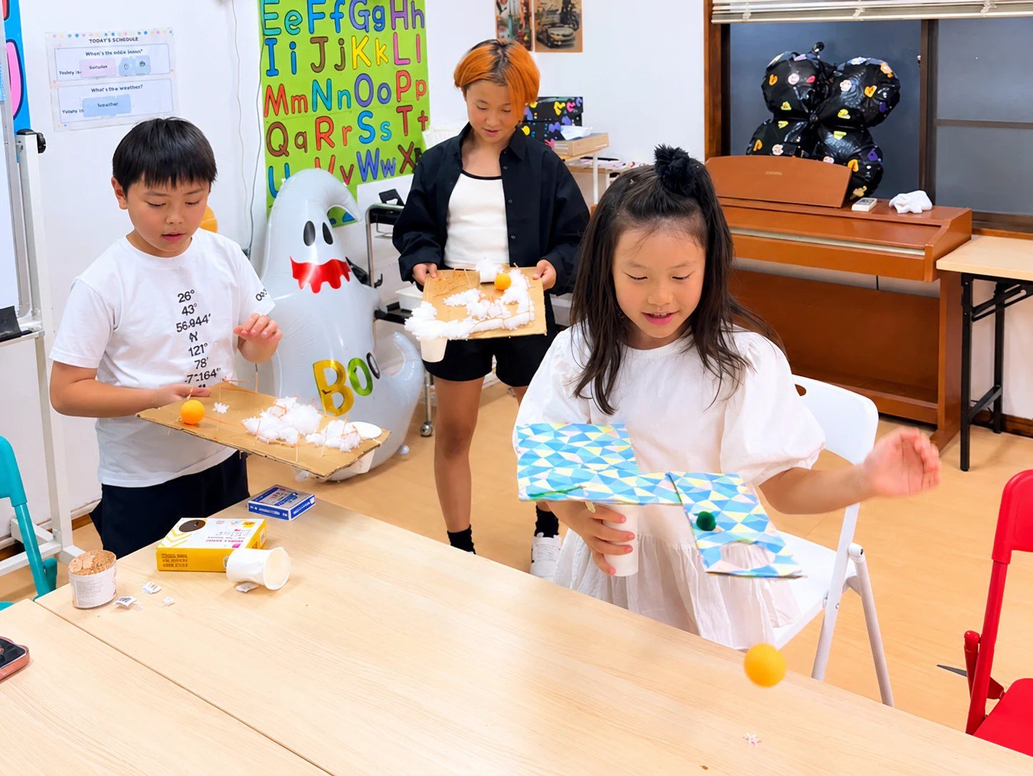 Children using handmade boards with balls attached by strings.