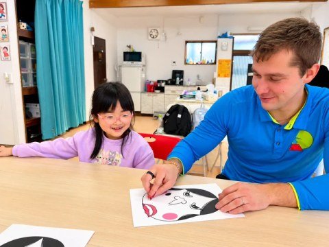 A teacher and child working on an activity with a picture of a face.