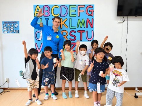 A teacher and children posing together in front of an alphabet display.