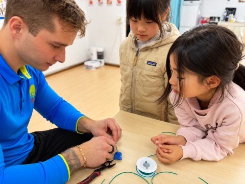 A teacher and children experimenting with batteries and electrical wires.