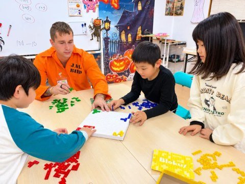 A teacher and children playing a board game with colorful tiles.